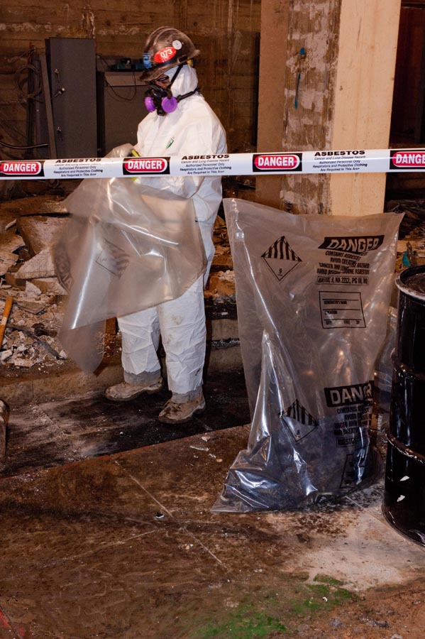 Operative bagging asbestos waste into labelled danger bags
